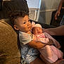 child, baby, couch, curly_hair, sleeping, holding, indoor, window, air_conditioner, pacifier, tattoo, pink_clothing, family, toddler, boy, newborn, love, care, soft_light, cozy