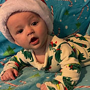 Emerson joined the competition — help win amazing prizes! baby, infant, santa_hat, pajamas, dinosaur_pattern, blanket, candy_cane, christmas_tree, holiday_theme, blue_blanket, cute, child, indoor, portrait, face, hands, expression, cozy, soft, lying_down