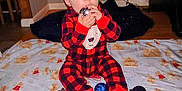 Odin is registered to the contest to win money with this photo: baby, child, christmas_tree, christmas_ornament, pajamas, blanket, gingerbread_man, holiday, indoor, floor, festive, decorations, lights, red, black, plaid, cute, sitting, toy, holiday_season