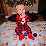 baby, child, christmas_tree, christmas_ornament, pajamas, blanket, gingerbread_man, holiday, indoor, floor, festive, decorations, lights, red, black, plaid, cute, sitting, toy, holiday_season