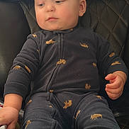 Odin joined the competition — help win amazing prizes! baby, child, onesie, moose_print, navy_blue, leather_chair, quilted, hand, face, sitting, indoor, curious, furniture, young_child, cozy, clothing, person, infant, soft_fabric, relaxed
