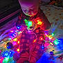 Odin is registered to the contest to win money with this photo: baby, child, lights, christmas_lights, colorful, plaid, onesie, holiday, festive, blanket, indoors, sitting, glowing, cute, face, red, decorations, cozy, toy, toddler