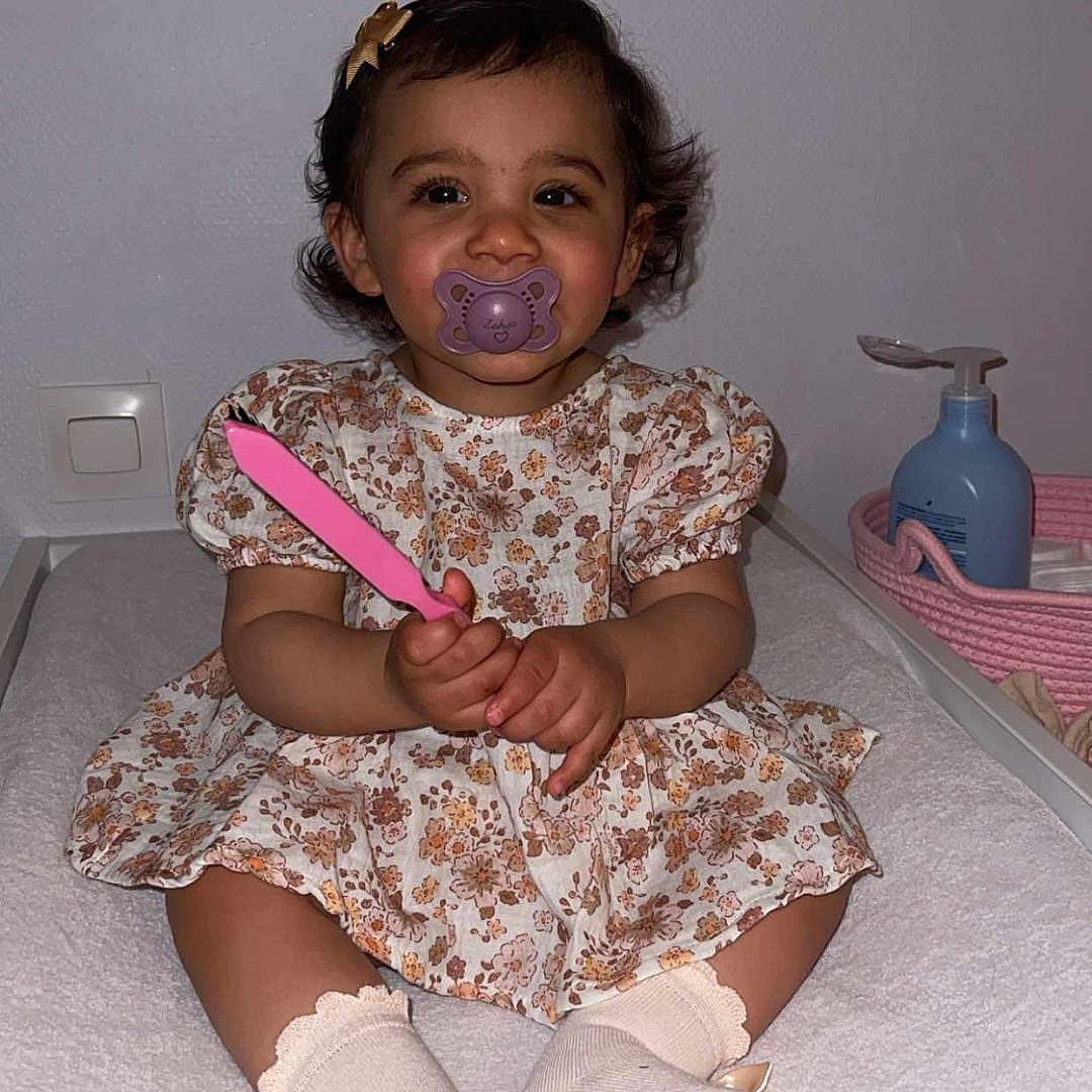 Zahya a rejoint le concours — aidez-le/la à gagner de superbes lots ! baby, baby_girl, basket, bow, changing_table, child, cozy, cute, floral_dress, indoor, infant, lotion_bottle, pacifier, person, pink, smiling, socks, toddler, toy, young_child