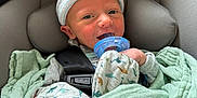 Theo joined the competition — help win amazing prizes! baby, newborn, pacifier, car_seat, blanket, beanie, infant, smiling, child, seatbelt, clothing, safety, cute, indoors, face, headwear, soft, wrapped, person, resting