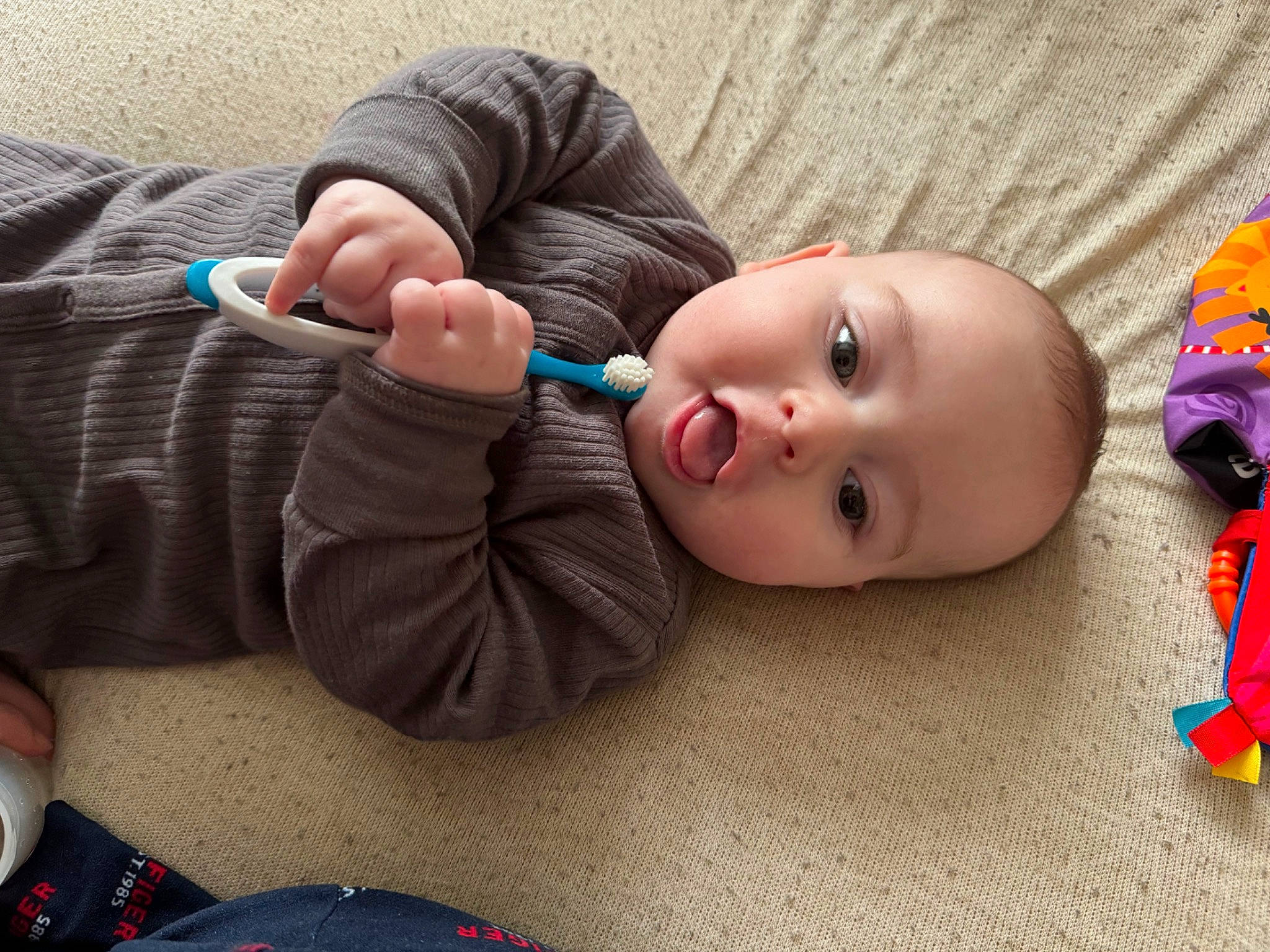 Xavier is registered to the contest to win money with this photo: baby, baby_toddler_clothing, cheek, chin, eye, eyelash, flooring, foot, fun, gesture, head, mouth, nail, nose, person, skin, thumb, toddler, toy, wood