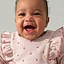 baby, smiling, happy, curly_hair, pink_outfit, polka_dots, ruffles, buttons, infant, portrait, child, cute, joyful, indoor, closeup, person, clothing, face, expression, young