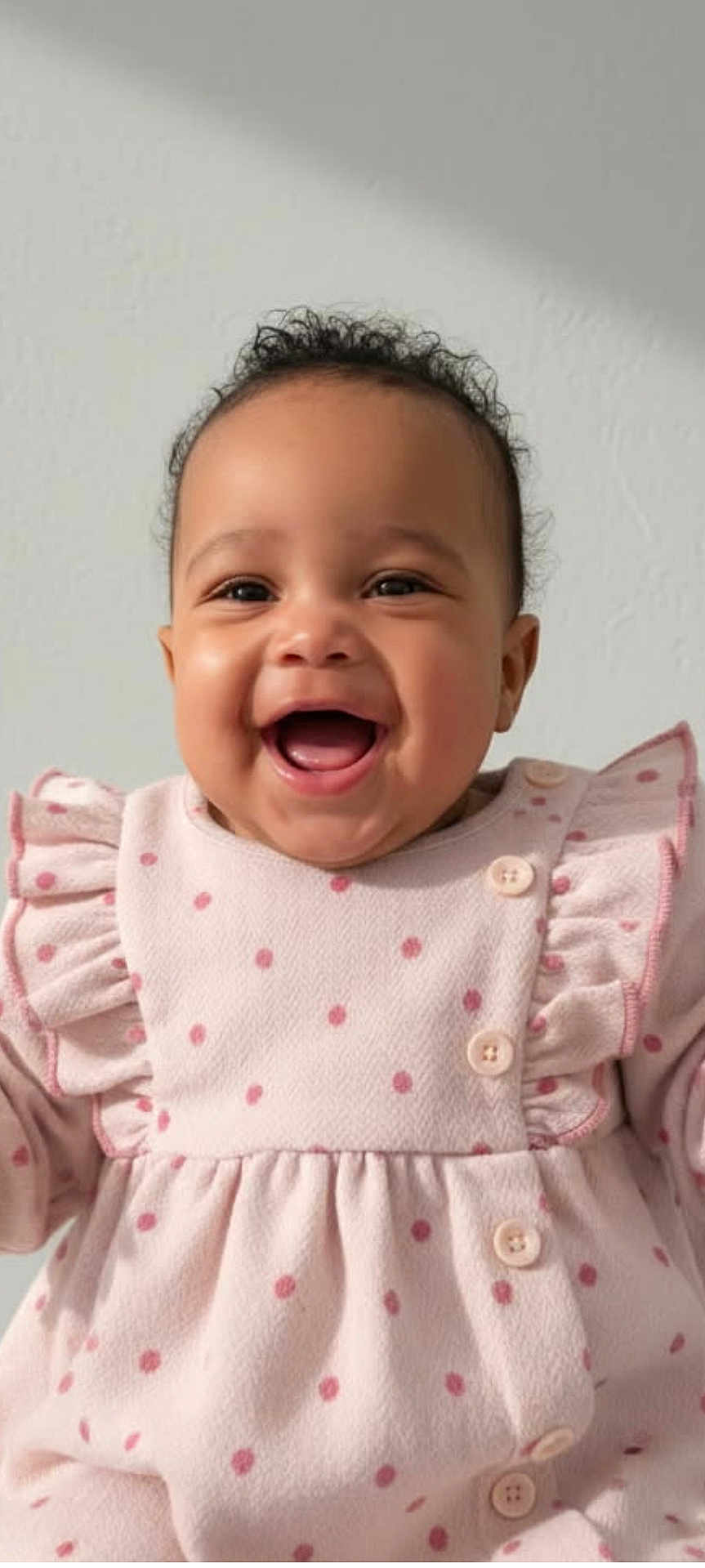 Mia a rejoint le concours — aidez-le/la à gagner de superbes lots ! baby, smiling, happy, curly_hair, pink_outfit, polka_dots, ruffles, buttons, infant, portrait, child, cute, joyful, indoor, closeup, person, clothing, face, expression, young