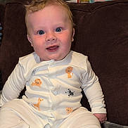 Mason joined the competition — help win amazing prizes! baby, child, infant, onesie, animal_print, smiling, blue_eyes, sitting, blanket, couch, indoor, happy, cute, face, young, person, soft_lighting, plush, comfort, portrait