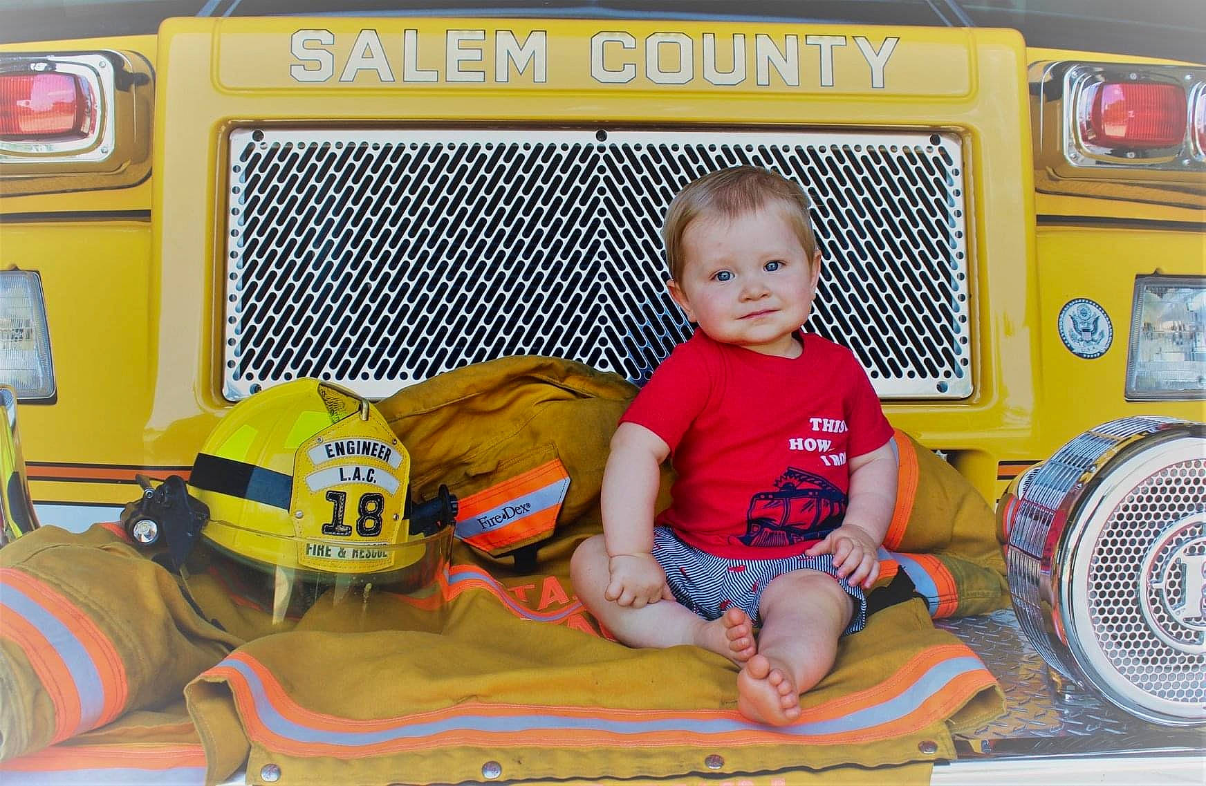Raylan is registered to the contest to win money with this photo: car, child, emergency_vehicle, fire_apparatus, firefighter, joy, mode_of_transport, person, play, school_bus, toddler, truck, truck_driver, vehicle, yellow
