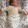 baby, newborn, sleeping, blanket, pajamas, cushion, floral_pattern, bed, infant, peaceful, soft_texture, indoors, resting, cute, child, person, comfortable, cozy, nap, sleep