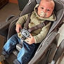 Elio participe au concours pour gagner de l'argent avec cette photo : baby, child, high_chair, pacifier, sweater, jeans, striped_socks, indoor, floor_tiles, table, trash_bin, face, person, seat_belt, furniture, wood, curious, infant, cozy, portrait