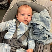 Elio participe au concours pour gagner de l'argent avec cette photo : baby, infant, car_seat, blanket, blue_clothing, cloud_pattern, straps, gray, indoor, child, face, sitting, comfort, toddler, safety, expression, hand, blanket_texture, home, relaxation