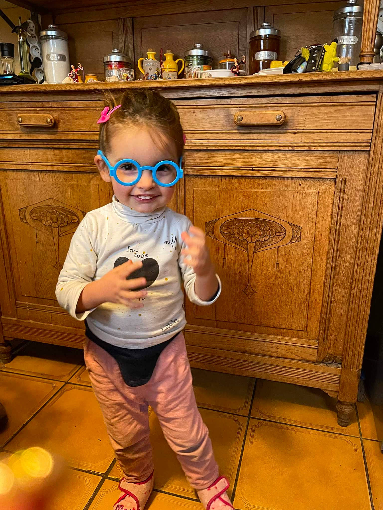 Rose Marie a rejoint le concours — aidez-le/la à gagner de superbes lots ! cabinetry, chest_of_drawers, countertop, drawer, eyewear, floor, flooring, fun, glasses, goggles, hairstyle, joy, kitchen, kitchen_appliance, major_appliance, person, smile, sunglasses, t_shirt, toddler