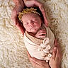 newborn, baby, sleeping, hands, flower_headband, blanket, swaddled, soft_texture, white_background, closeup, portrait, infant, tenderness, care, family, peaceful, rest, skin, adult_hands, comfort
