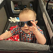 Zachery joined the competition — help win amazing prizes! toddler, child, sunglasses, playpen, checkered_shirt, toy, blanket, indoor, baby, face, hand, person, cute, casual_clothing, infant, young_child, furniture, home, portrait, smiling