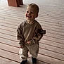 toddler, child, smiling, sweatshirt, pants, shoes, wooden_deck, outdoor, happy, person, casual_clothing, cute, standing, young_child, daylight, playful, patch, fabric, feet, portrait