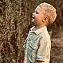 child, blonde_hair, smiling, profile_view, outdoor, greenery, nature, shirt, short_sleeves, young_boy, innocent, happy, portrait, casual_clothing, daylight, standing, cute, person, background_blur, face