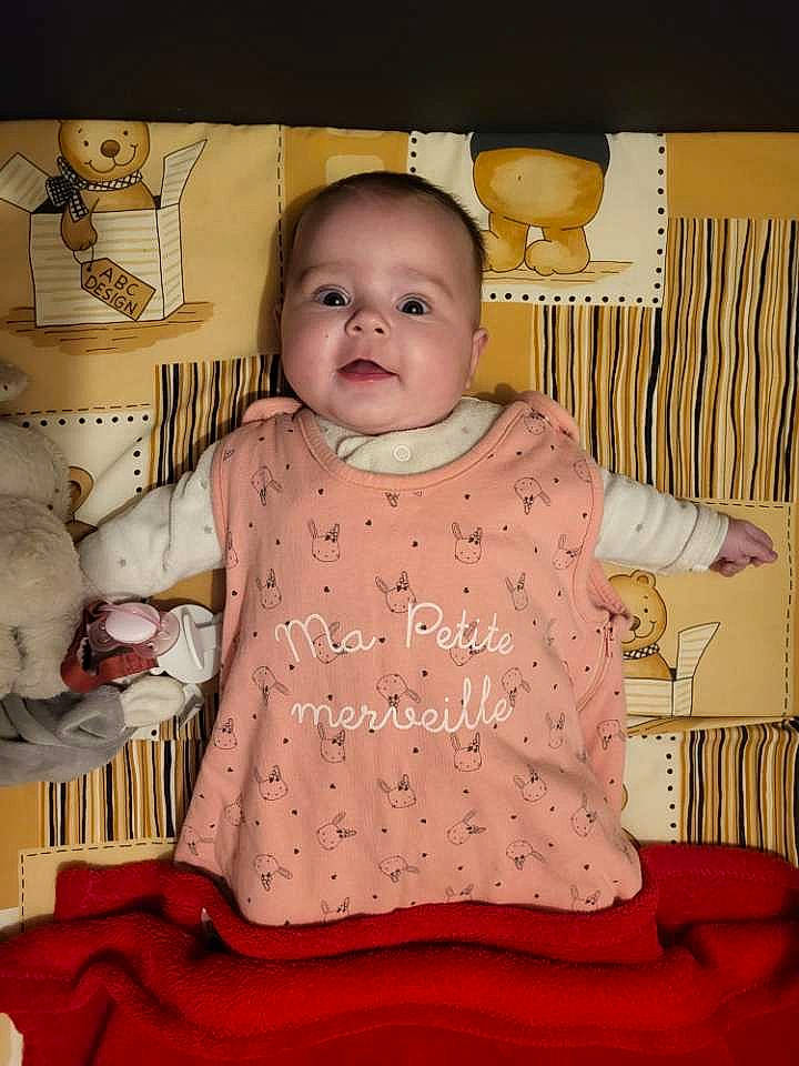 éléa participe au concours pour gagner de l'argent avec cette photo : abdomen, baby, baby_products, baby_toddler_clothing, cheek, child, comfort, happy, linens, pattern, peach, person, pink, room, sitting, sleeve, t_shirt, toddler, toy, white