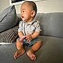 Mateo is registered to the contest to win money with this photo: baby, child, smiling, clapping, couch, pillow, indoors, happy, person, shirt, shorts, foot, hand, seated, home, infant, cute, skin, face, living_room