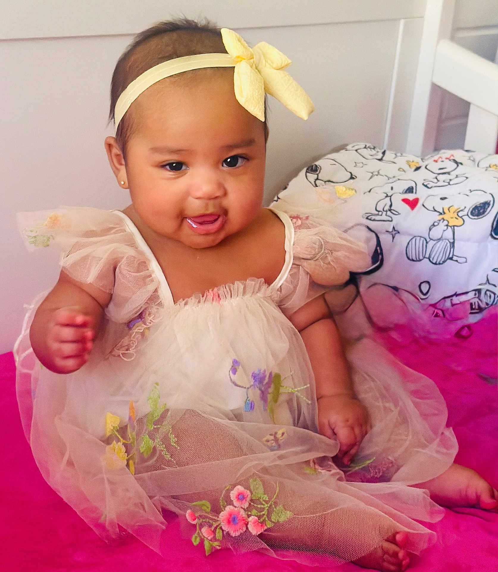 Florencia joined the competition — help win amazing prizes! baby, child, dress, headband, yellow_bow, smile, drool, sitting, pink_surface, bedroom, bedding, snoopy, cartoon, cute, portrait, indoors, infant, adorable, happy, tulle
