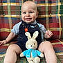 Johnny joined the competition — help win amazing prizes! baby, child, smiling, indoor, plush_toy, bunny, overalls, couch, patterned_fabric, happy, cute, sitting, toy, infant, person, face, arm, leg, clothing, comfort