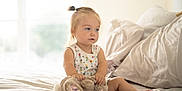 Piper is registered to the contest to win money with this photo: baby, bed, blond_hair, casual_clothing, child, comfort, cute, daylight, home, indoor, person, pony_tail, portrait, relaxed, sitting, soft_light, stuffed_animal, toddler, toy, white_bed