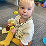 Piper joined the competition — help win amazing prizes! toddler, child, blonde_hair, pigtails, blue_eyes, sitting, carpet, toy, cookie, playroom, yellow_socks, white_sweater, floral_dress, indoor, floor, curious, innocent, expression, young_child, cute