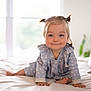 toddler, child, baby, crawling, bed, blue_clothing, polka_dot, pigtails, smiling, indoor, window, natural_light, cute, happy, person, home, soft, blanket, foot, hand