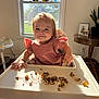 Piper is registered to the contest to win money with this photo: toddler, child, high_chair, food, messy, smile, indoor, window, sunlight, meal, baby, table, pink_dress, happy, face, furniture, plant, home, floor, daylight