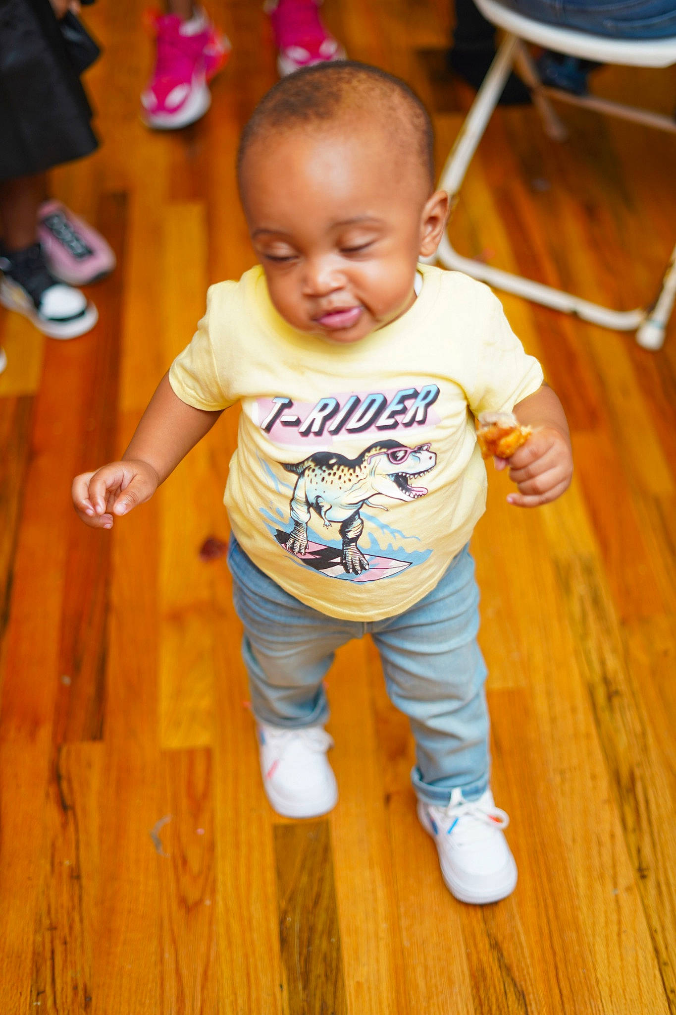 Aston is registered to the contest to win money with this photo: baby, child, floor, flooring, fun, person, play, shoe, smile, standing, t_shirt, toddler, wood