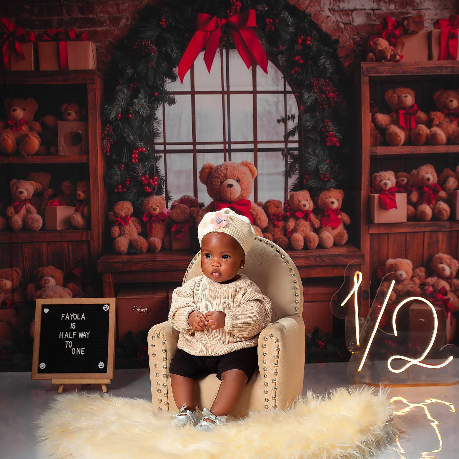 Fayola is registered to the contest to win money with this photo: baby, child, chair, teddy_bear, holiday_decor, gift_box, window, rug, knit_hat, sweater, floor, signboard, light_number, red_bow, wooden_shelves, plush_toy, indoor, portrait, celebration, smiling