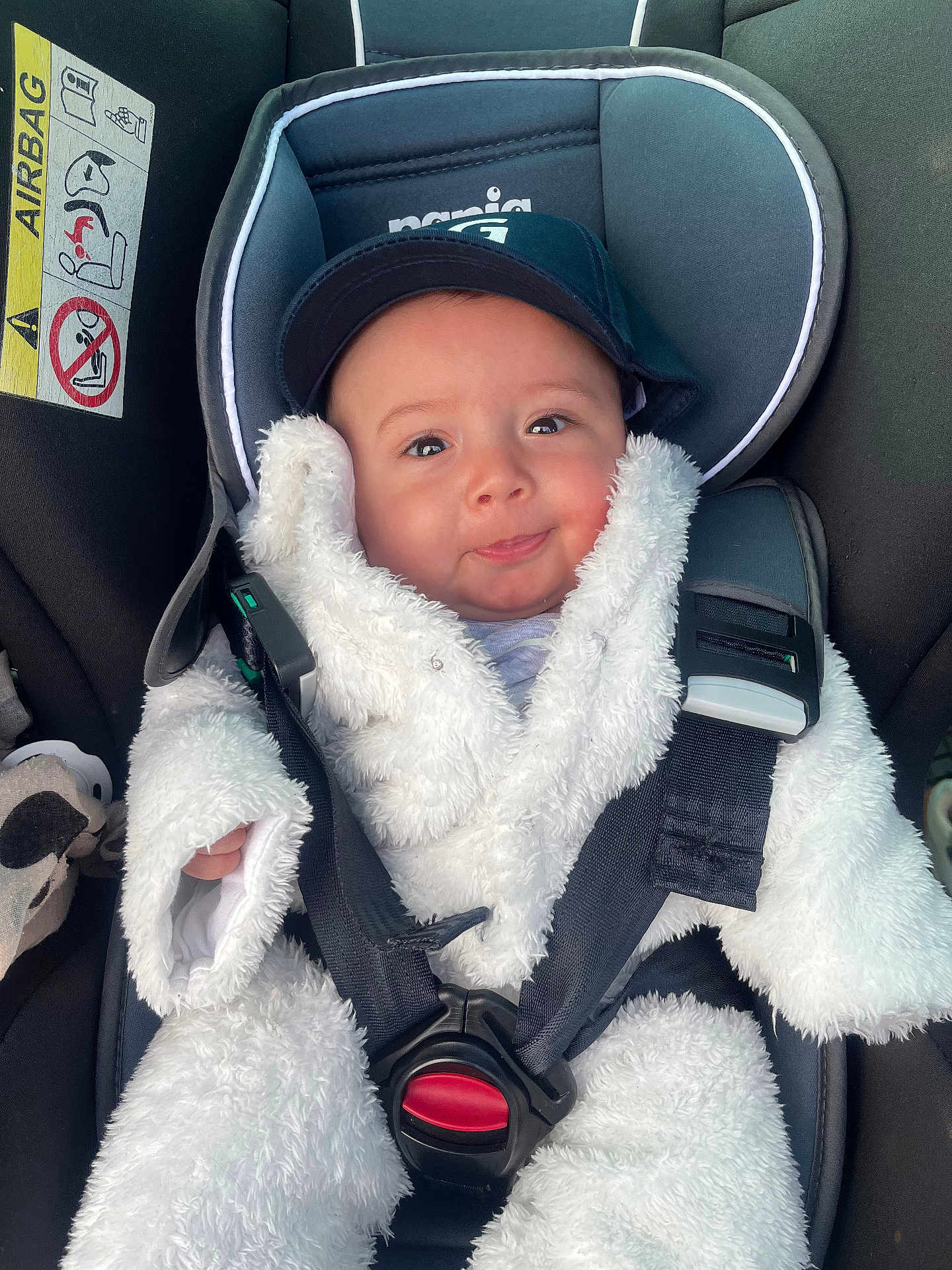 Livio participe au concours pour gagner de l'argent avec cette photo : baby, child, car_seat, seat_belt, fluffy_clothing, hat, smile, face, infant, safety, car_interior, cute, young_child, portrait, strapped_in, cozy, white_clothing, cap, infant_clothing, close_up