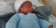 Livio a rejoint le concours — aidez-le/la à gagner de superbes lots ! newborn, baby, sleeping, blue_clothing, knit_hat, hospital, blanket, hand, medical_tube, infant, bed, cozy, peaceful, cute, person, child, small_hands, swaddled, soft_light, resting