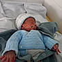 newborn, baby, sleeping, blue_clothing, knit_hat, hospital, blanket, hand, medical_tube, infant, bed, cozy, peaceful, cute, person, child, small_hands, swaddled, soft_light, resting