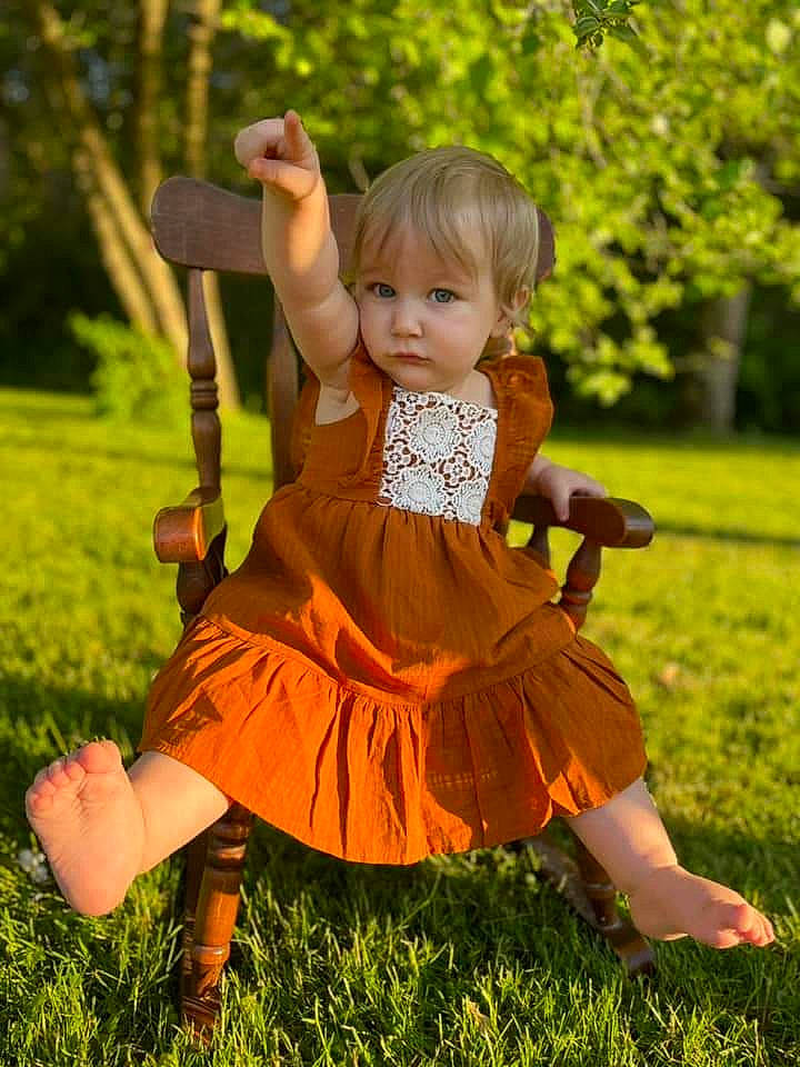 Brooklynn is registered to the contest to win money with this photo: dress, eye, face, fawn, fun, grass, hair, hand, happy, head, musical_instrument, nature, orange, people_in_nature, person, pink, plant, summer, sunlight, toddler