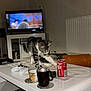 Gribouille participe au concours pour gagner de l'argent avec cette photo : cat, tabby_cat, coffee_table, coca_cola_can, mug, game_controller, television, living_room, carpet, book, remote_control, orange_cushion, white_furniture, curious_cat, indoor, electronics, drink, tableware, pet, household