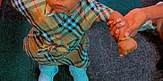 Keeayla is registered to the contest to win money with this photo: toddler, child, indoor, carpet, holding_hand, dress, white_bows, sneakers, adult_hand, person, legs, chair, red_chair, patterned_clothing, hairstyle, jewelry, floor, support, curious, standing