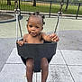 barefoot, black_hair, bucket_swing, child, concrete, cute, daytime, fence, grass, happy, outdoor, park, person, play_area, playground, smiling, swing, toddler, trees, young_child