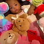 baby, blanket, child, colorful, cozy, cute, face, grinch, indoor, infant, lying_down, pink_clothing, plush_toys, portrait, relaxed, santa_hat, soft_toys, stuffed_animals, teddy_bear, toy_collection