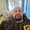 Beaver Cleaver is registered to the contest to win money with this photo: man, kitten, sleeping, indoor, window, tree, chair, beard, mustache, closed_eyes, brown_jacket, yellow_trim, blanket, couch, relaxing, pet, animal, feline, comfort, rest