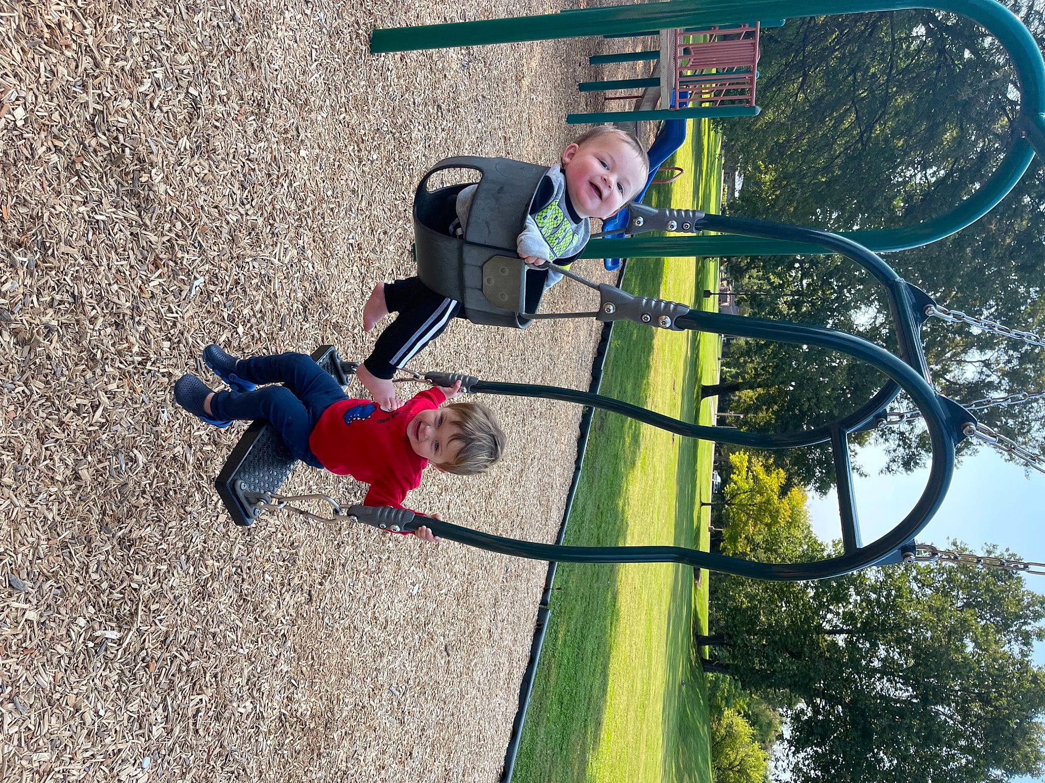 Ashtyn is registered to the contest to win money with this photo: baby, basketball_hoop, city, fun, grass, leisure, outdoor_play_equipment, person, plant, play, playground, pole, public_space, recreation, shadow, sky, soil, sports_equipment, tire, toddler