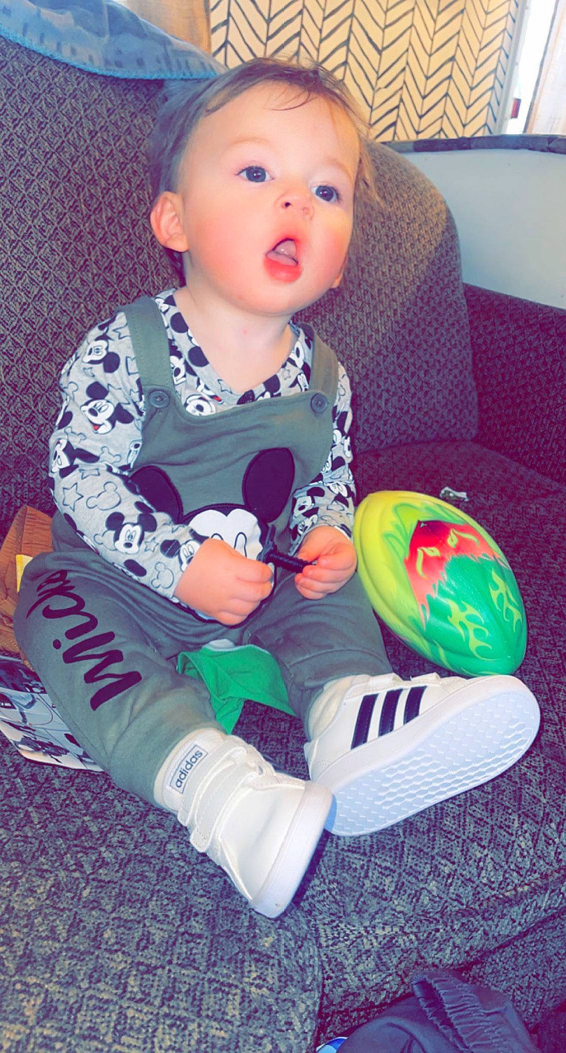 Ashtyn is registered to the contest to win money with this photo: baby, baby_playing_with_toys, baby_toddler_clothing, cheek, child, comfort, couch, face, fun, happy, head, human_body, pattern, person, sitting, skin, sleeve, sock, surprise, t_shirt