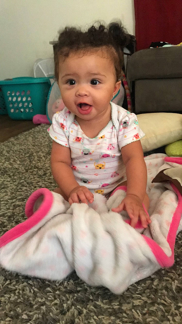 Dominique is registered to the contest to win money with this photo: baby, baby_toddler_clothing, cheek, child, head, mouth, person, pink, play, sitting, skin, smile, toddler