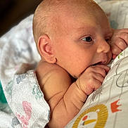 Jaxson is registered to the contest to win money with this photo: baby, blanket, child, closeup, cute, face, hand, indoors, infant, lying_down, newborn, pattern, peaceful, portrait, skin, sleepy, soft, sucking, toddler, wrapped