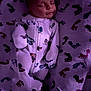 baby, sleeping, onesie, blanket, footprint_pattern, infant, cute, cozy, soft_texture, colorful, patterned, child, bedtime, peaceful, clothing, indoor, portrait, resting, newborn, warm