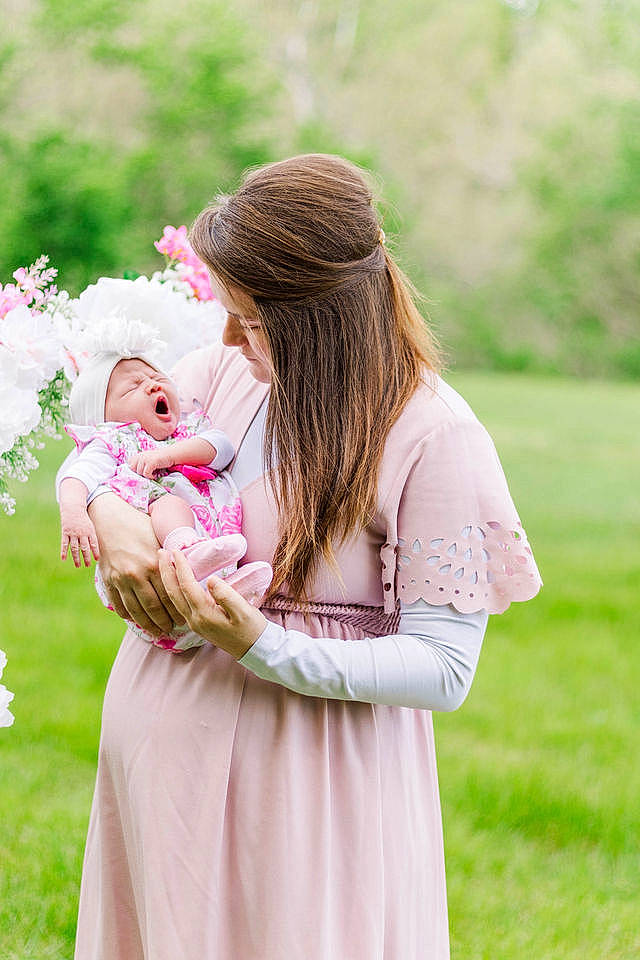 Izzabella is registered to the contest to win money with this photo: baby, bridal_clothing, cap, dress, event, fashion_accessory, gesture, gown, grass, grassland, happy, headgear, headwear, jewellery, peach, people_in_nature, person, pink, plant, sitting
