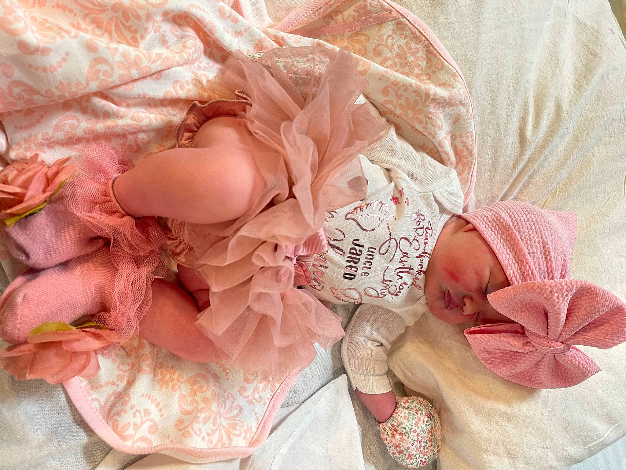 Izzabella is registered to the contest to win money with this photo: baby, baby_toddler_clothing, child, comfort, embellishment, event, fashion_accessory, flower, hair_accessory, headgear, headwear, leg, pattern, peach, person, petal, pink, plant, rose, rose_order