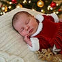 Malena is registered to the contest to win money with this photo: baby, sleeping, red_dress, white_fur_trim, knit_blanket, christmas_tree, ornaments, holiday, festive, plush_toy, reindeer, glitter, soft_focus, portrait, indoors, cozy, celebration, child, peaceful, decor
