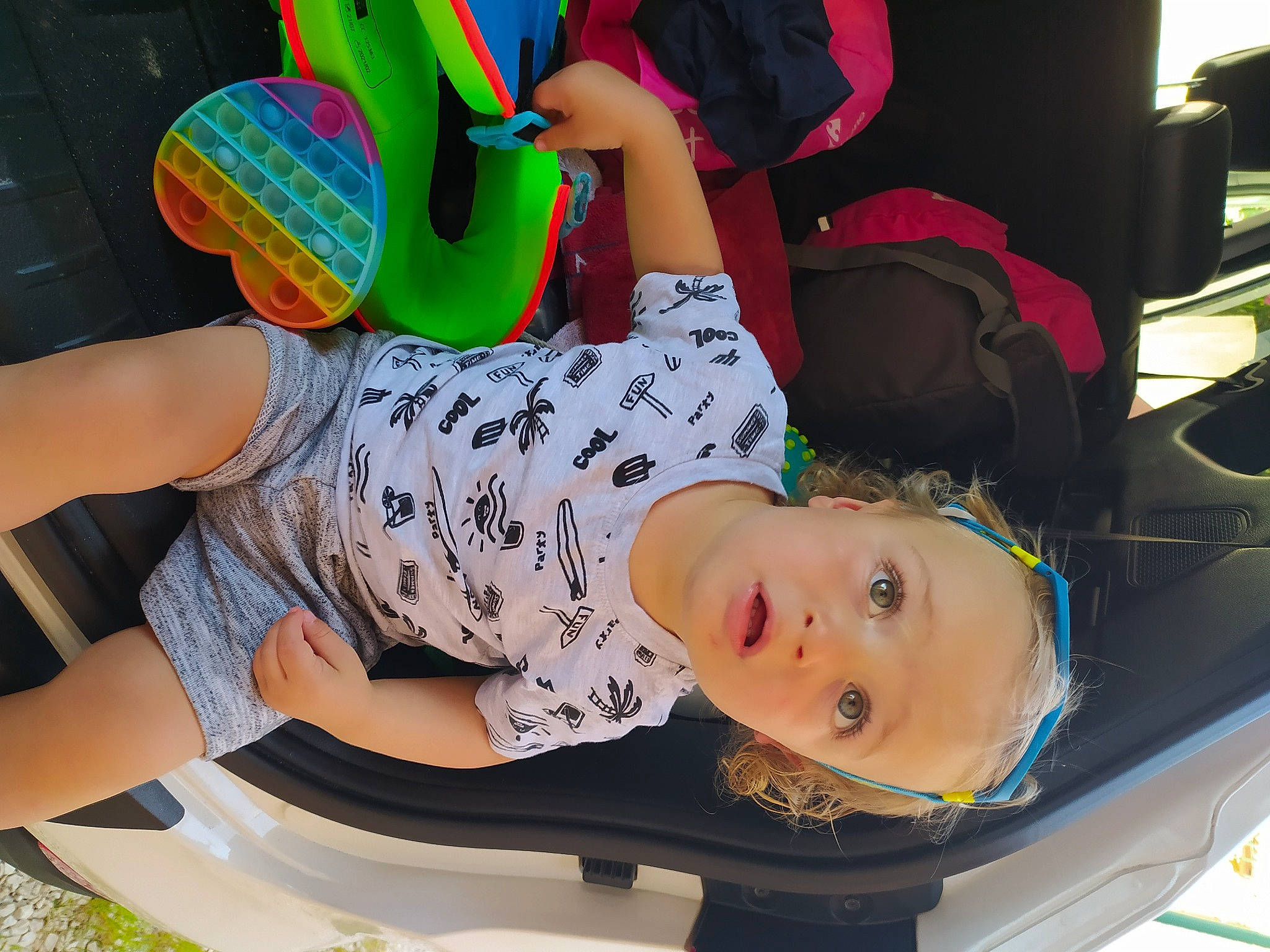 Valentino participe au concours pour gagner de l'argent avec cette photo : automotive_exterior, baby, baby_products, baby_toddler_clothing, chair, child, family_car, fun, happy, human_leg, knee, leisure, motor_vehicle, party_supply, person, sandal, sitting, surprise, t_shirt, thigh