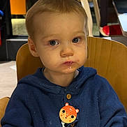 Liam participe au concours pour gagner de l'argent avec cette photo : blonde_hair, blue_hoodie, child, drooling, eating, eyes, face, fire_extinguisher, highchair, indoor, pacifier_clip, portrait, restaurant, seat, serious_expression, shallow_depth_of_field, table, toddler, wooden_chair, wooden_furniture